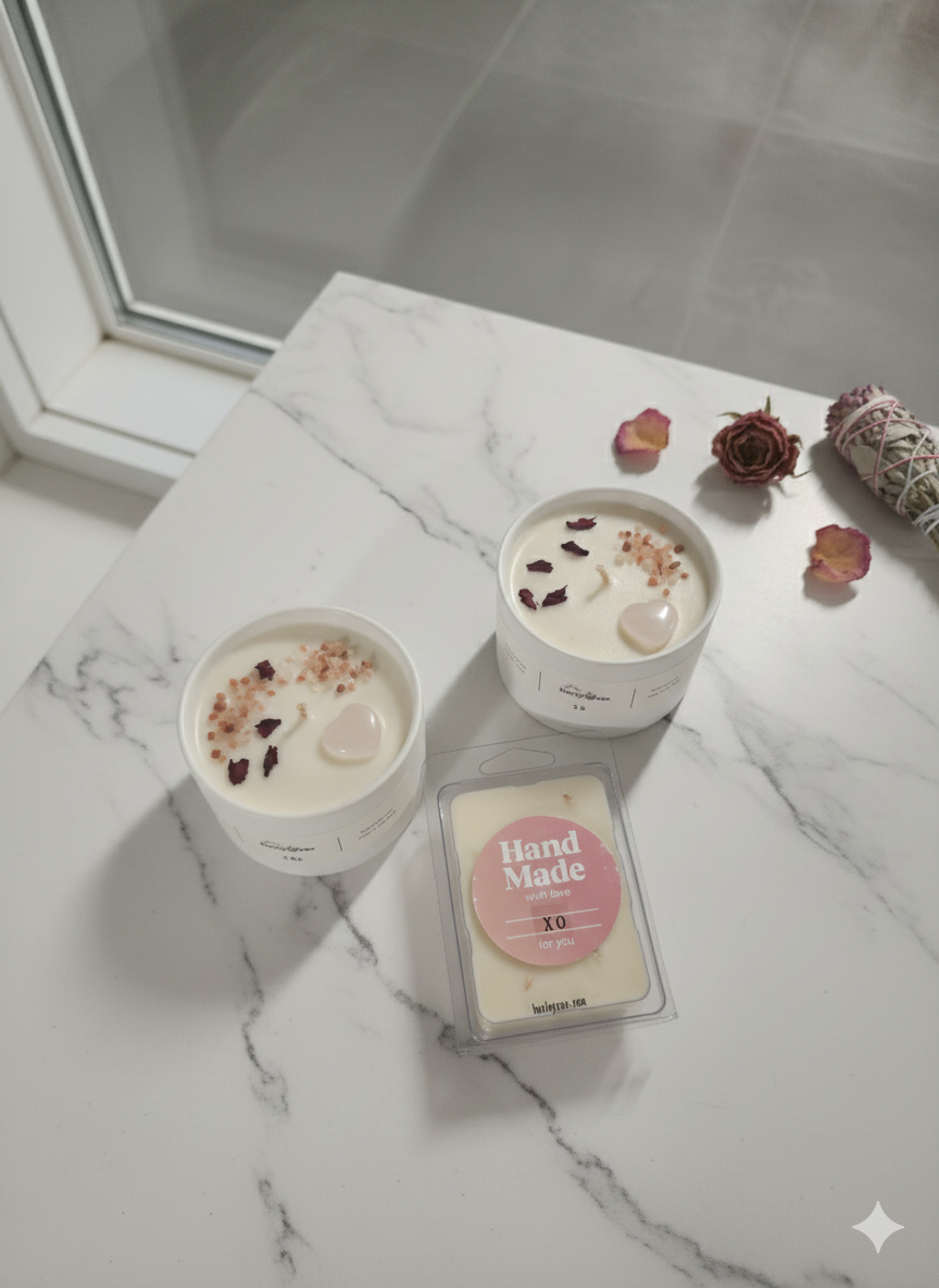 Two small candles with decorative elements on a marble surface, accompanied by a 'Hand Made' sign.